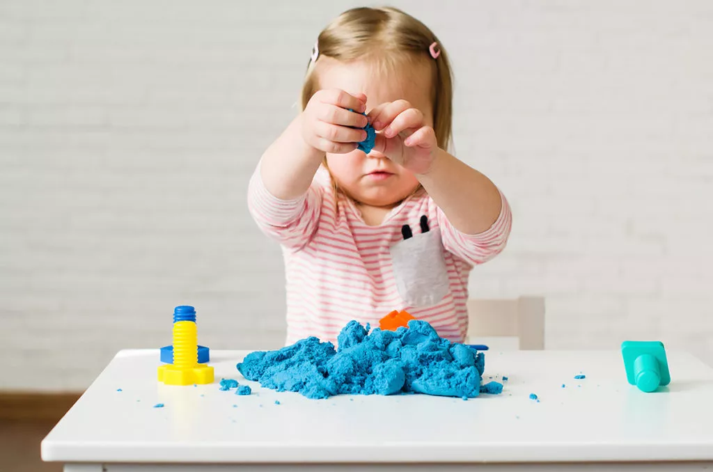 Little girl playing with blue kinetic sand at a preschool in Potomac, MD