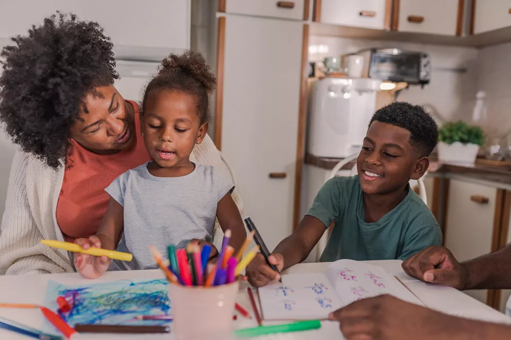 Mother talking, playing and coloring with her son and daughter at a table