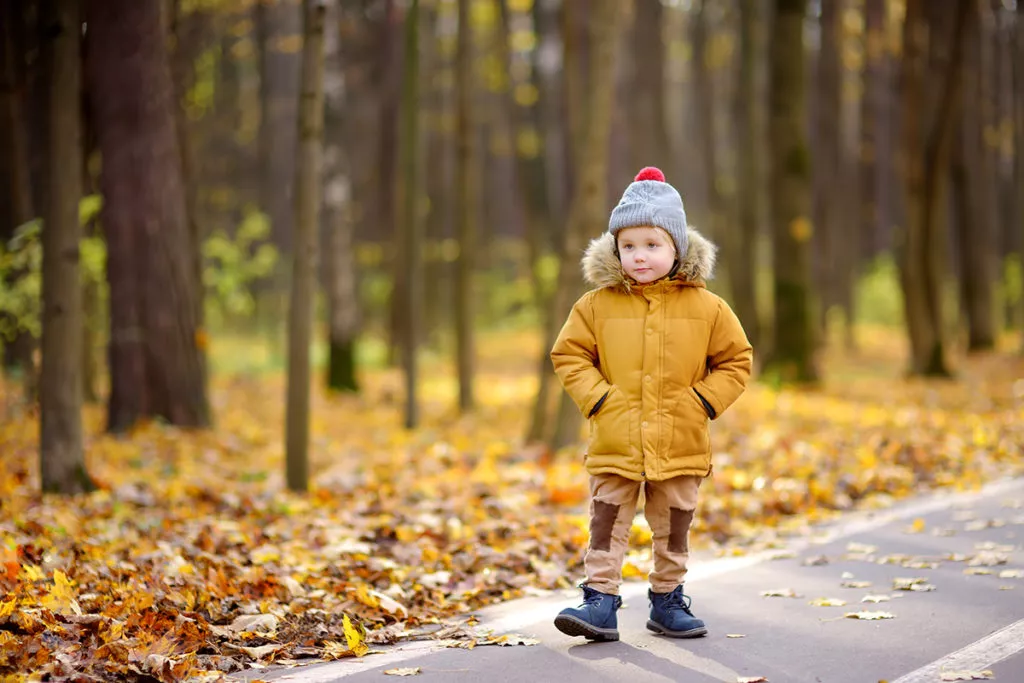 Little boy walking outside in his warm jacket, hat, and boots on a cold day in Rockville, MD