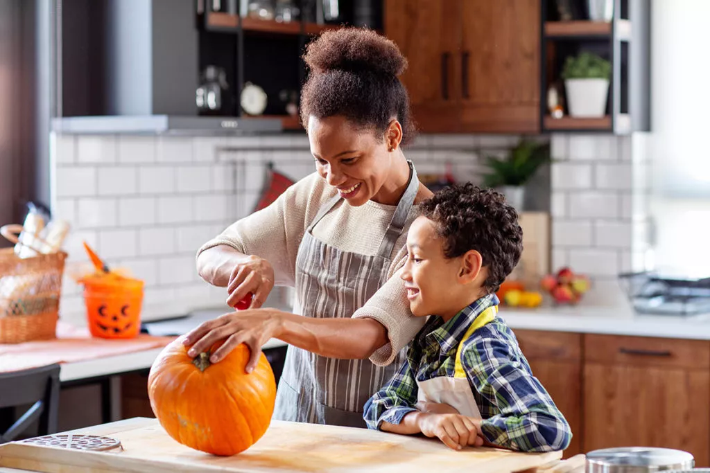 Woman with her son in the kitchen prepare pumpkin for a volcano experiment.