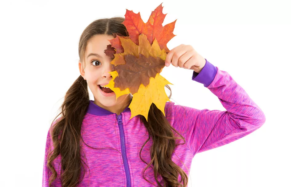 Young girl holding autumn leaves by her face for Fun Fall Crafts
