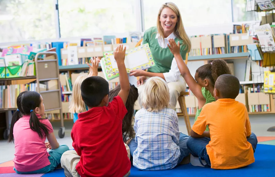 Kindergarten teacher reading to children in library