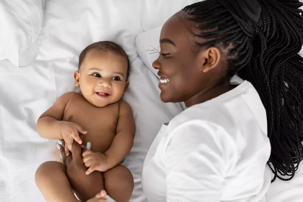 Mother spending time with her baby in bed as part of a healthy bed time routine.
