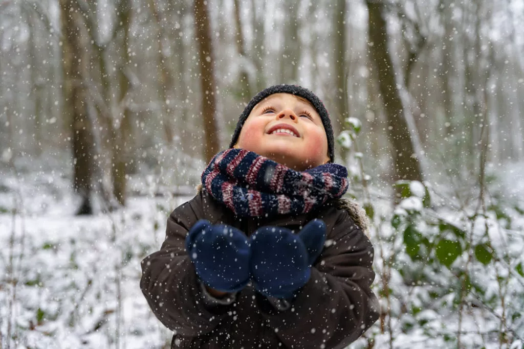 Closeup of a happy boy enjoying a cold and snowy day in Rockville, MD wearing his warm coat, gloves and hat.