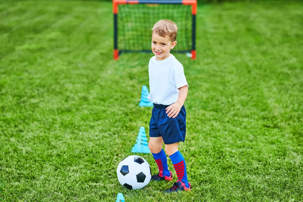 Little Boy practicing soccer outdoors