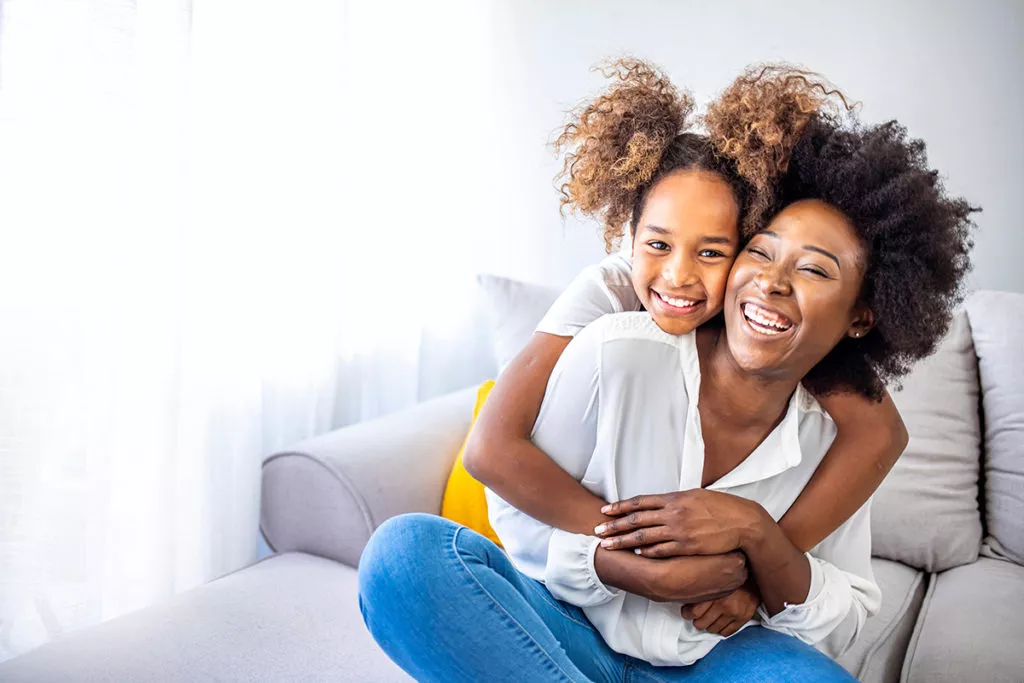 Mother and daughter smiling and hugging, using positive reinforcement to build confidence.
