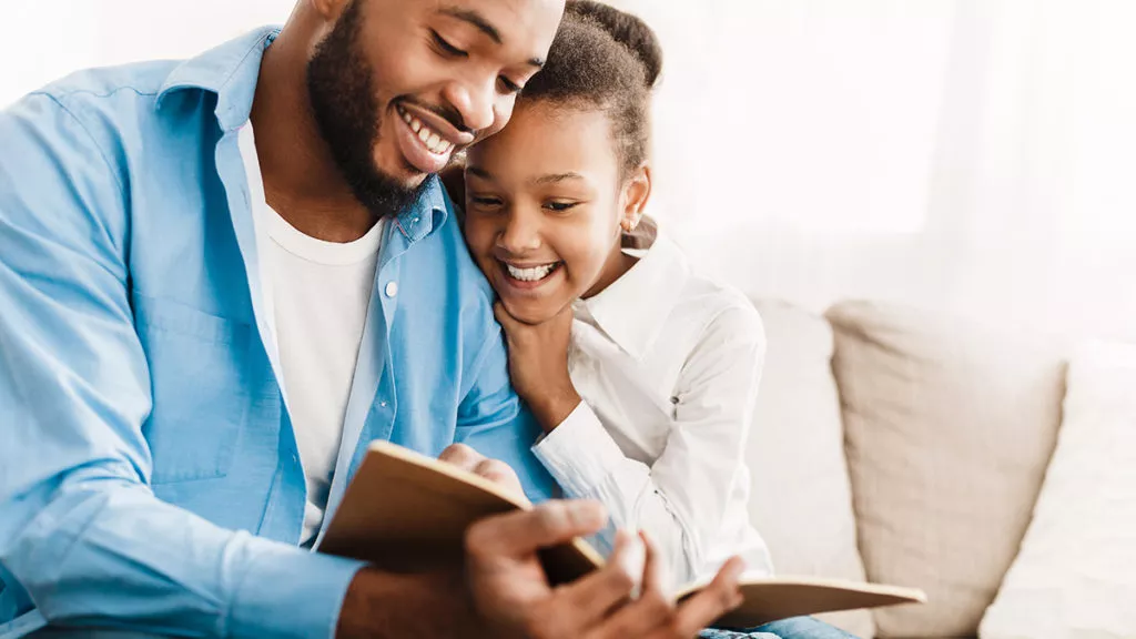 Father and daughter reading a book about kindness and empathy together
