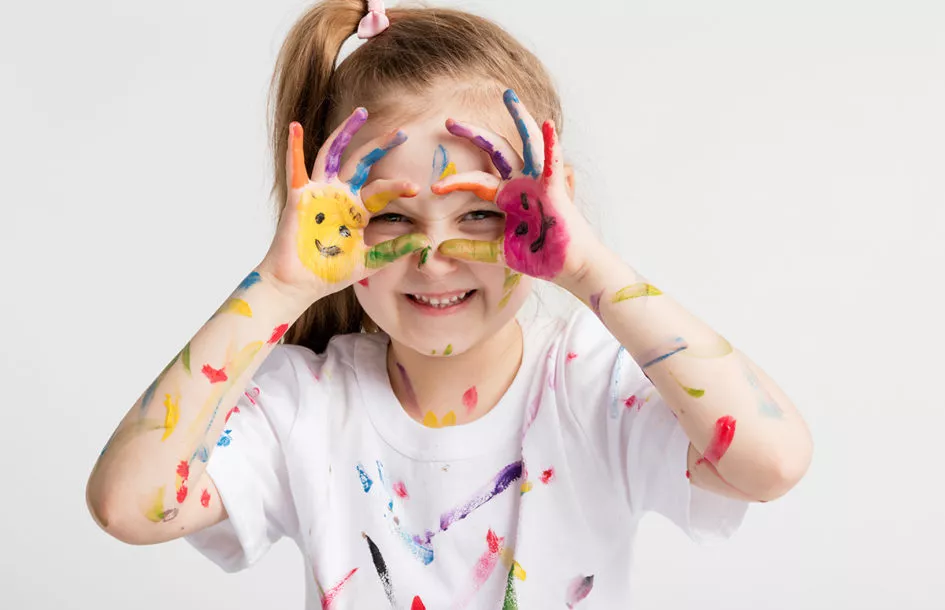 Little girl covered in paint making funny faces.