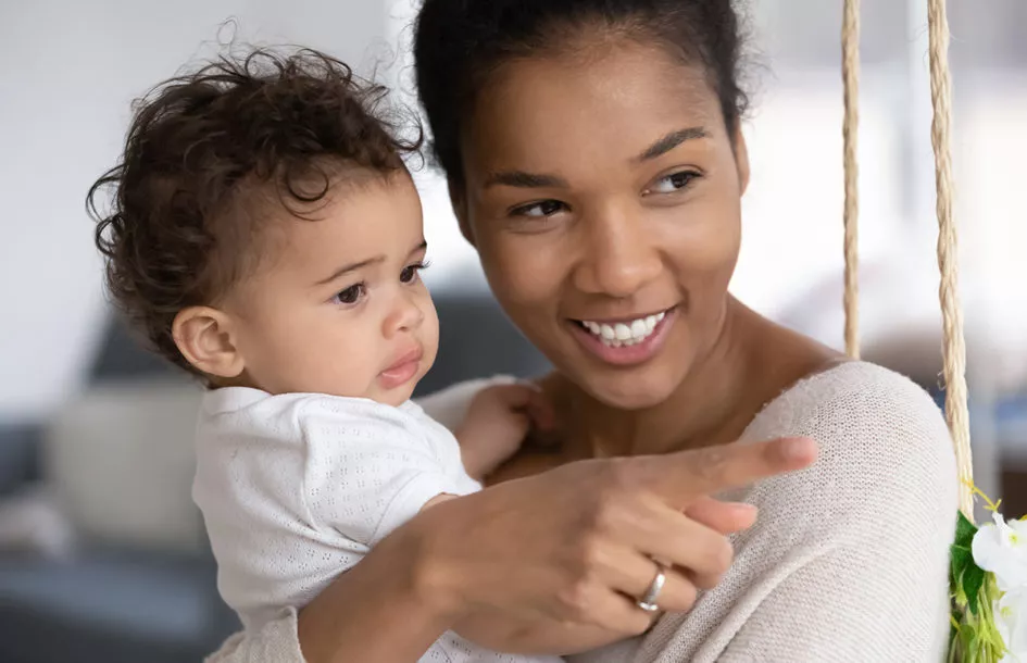 Close up of happy young African American mom holding and talking to her cute little baby.