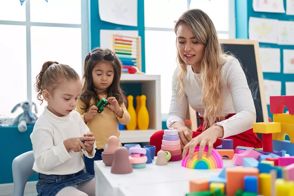 Teacher playing with blocks at a table in preschool in MD.