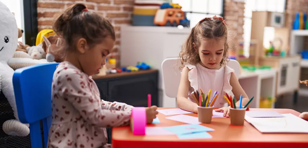 Two kids sitting at a table and painting at a preschool in MD.