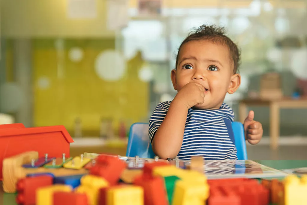 Happy baby playing with toy blocks the Rockville infant daycare center.