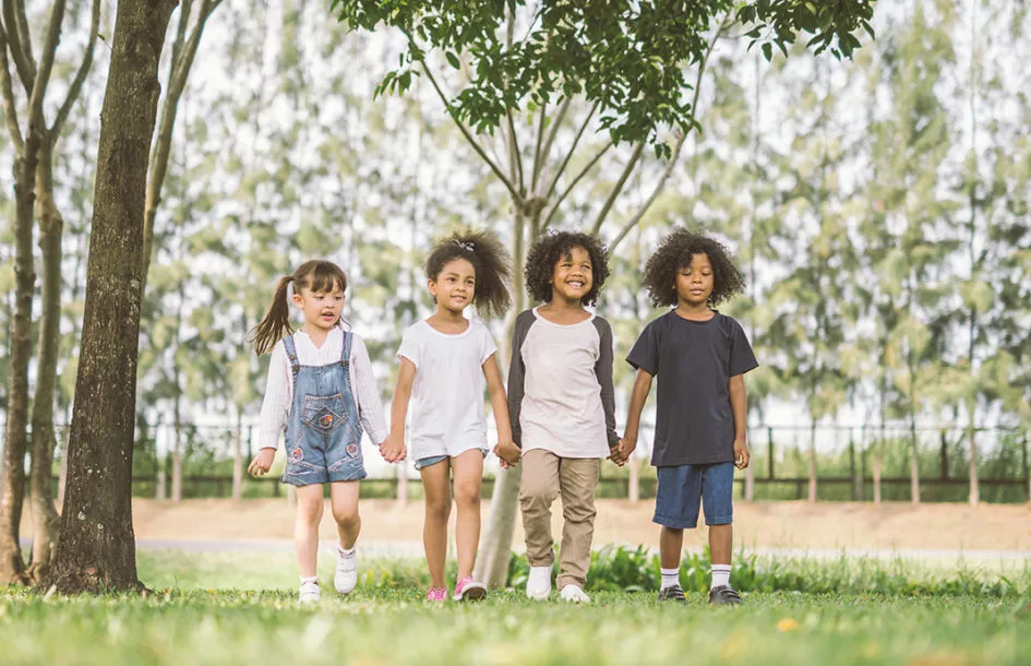 Preschool kids holding hands and smiling to show how Preschool teaches Kids How to Make Friends.