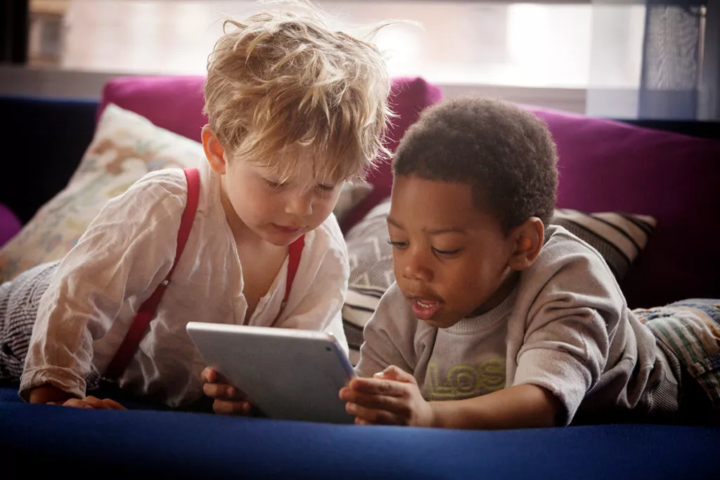 2 toddler boys looking at a table for screen time.
