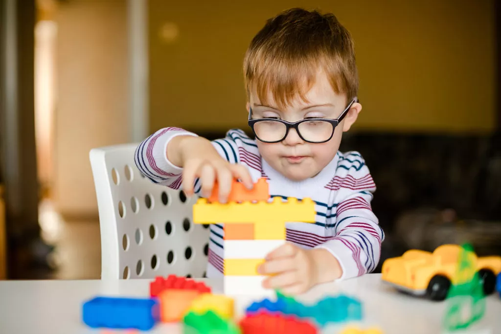 Little boy playing with building blocks to build motor skills at home.