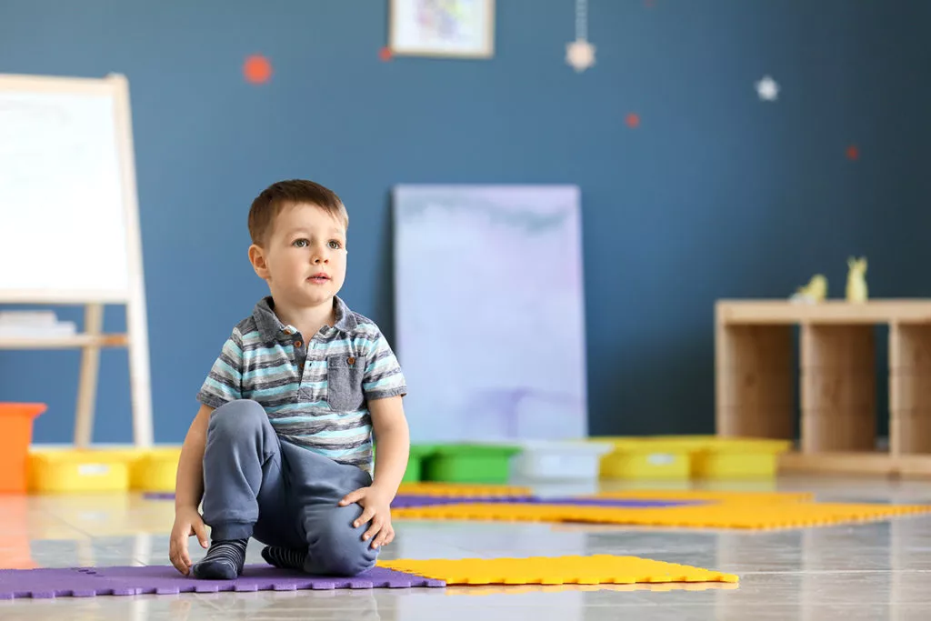 Little boy at a preschool in Olney, MD sitting and learning and listening to his preschool teacher to learn phonics.
