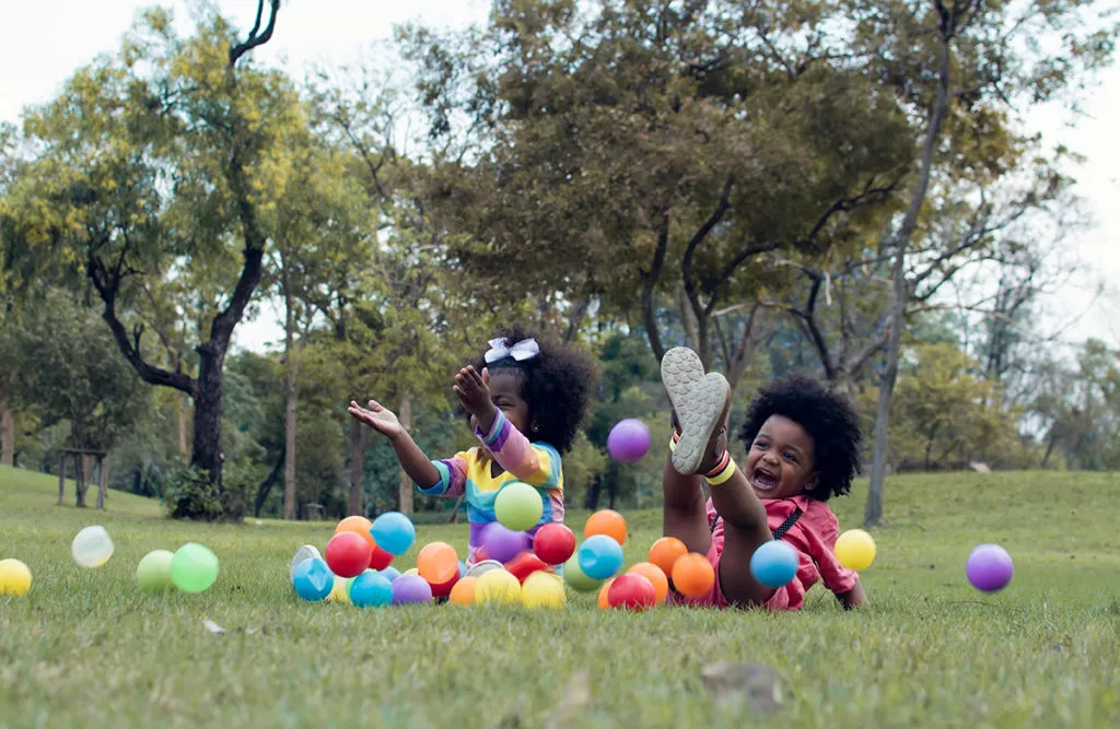 2 preschool kids enjoying playtime outside at a preschool in Silver Spring while playing with colorful balls and leaning to make friends.