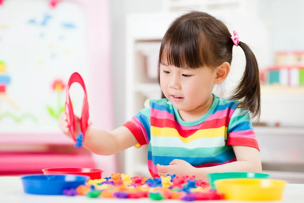 A young girl at a preschool in North Potomac, MD, learning early communication skills while practicing math and color sorting skill game.