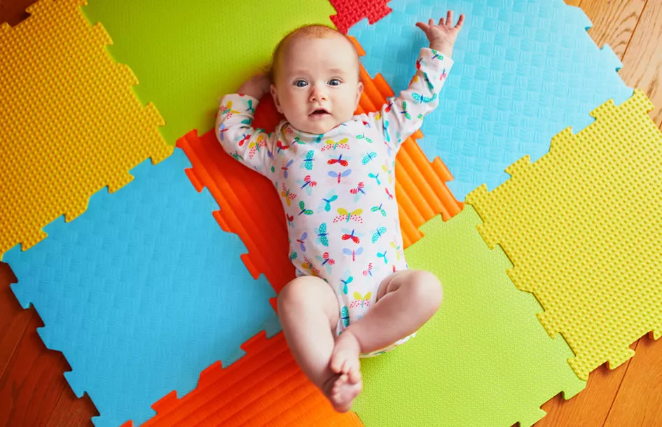 A baby girl lying on colorful play mat at an infant daycare in Rockville.
