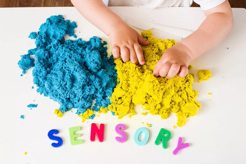 a closeup of a child in a Potomac, MD preschool engaging in sensory play at a table while learning early communication skills.