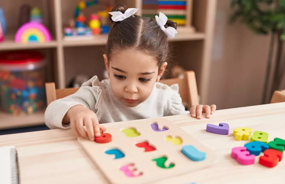 Adorable preschool girl playing with a numbers puzzle game to learn early math and numbers.