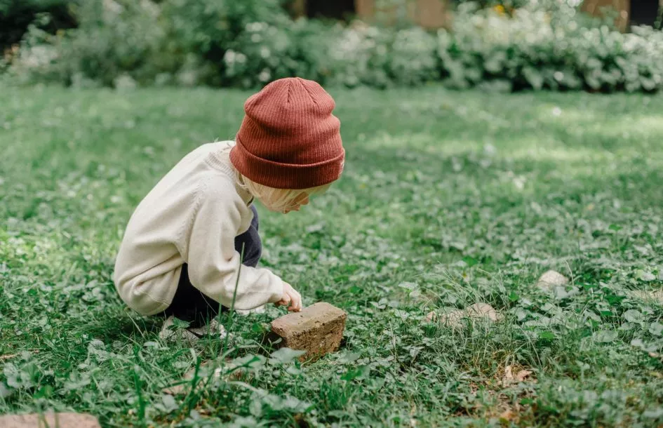 Preschool aged boy playing outside observing nature