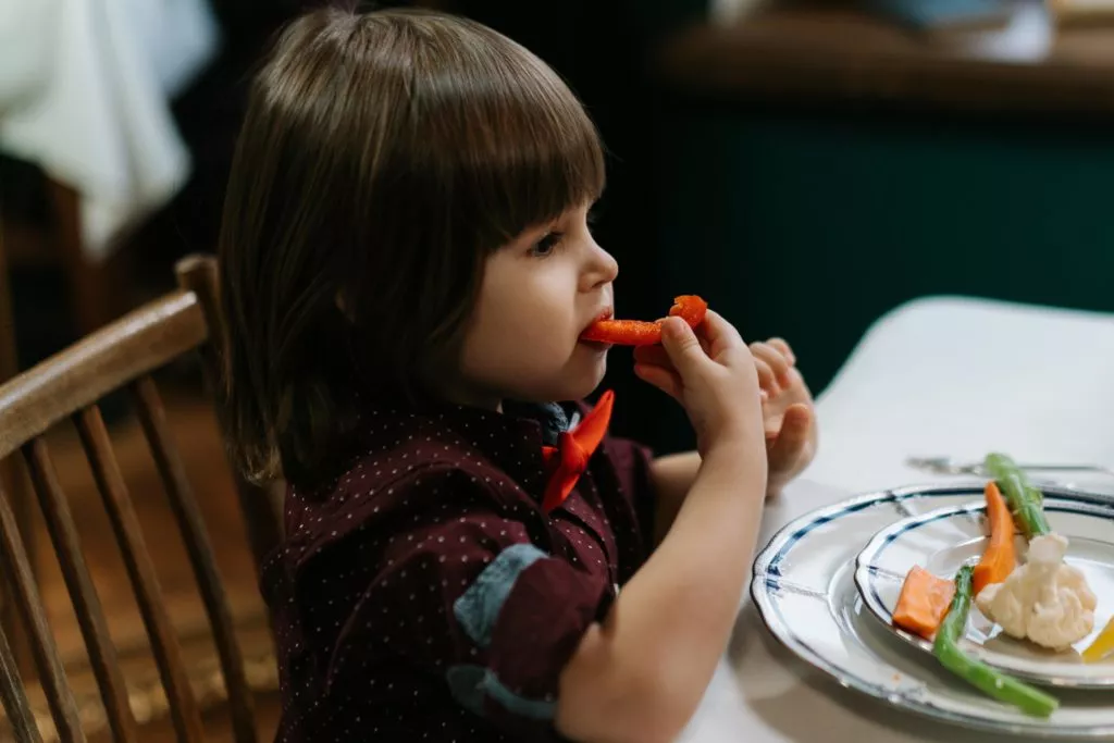 pre-school age little girl eating vegetables