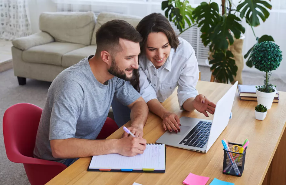 High angle of husband writing in notebook planning for emergency childcare