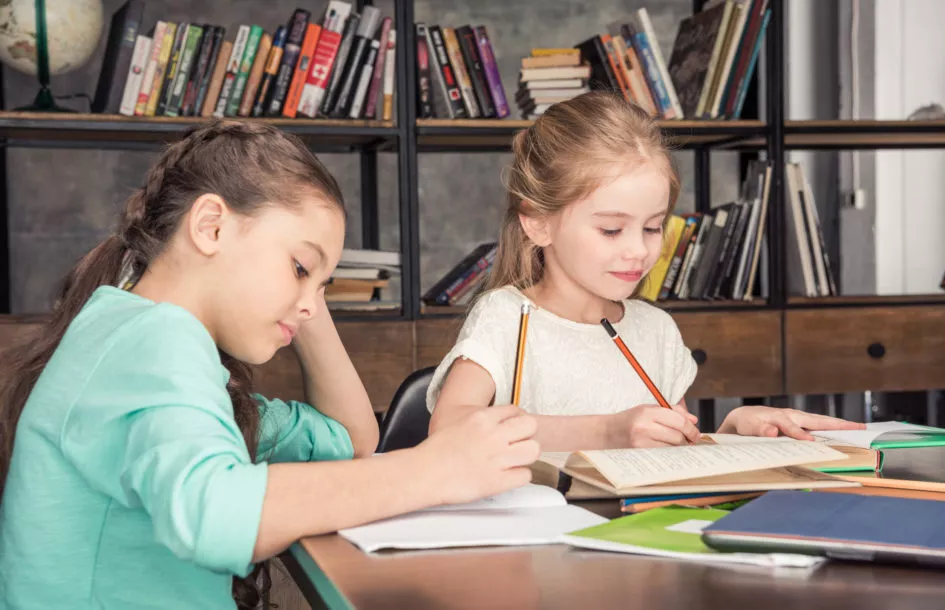 two girls concentrated on their school homework routine