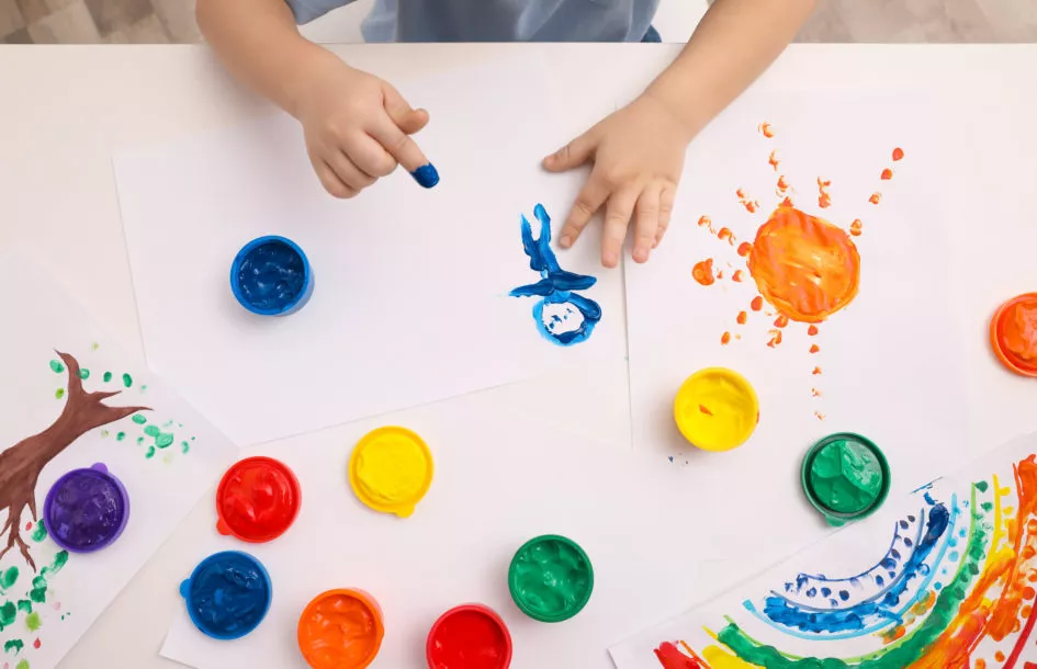 Fun weekend activities for toddlers: Little child painting with finger at white table indoors, top view
