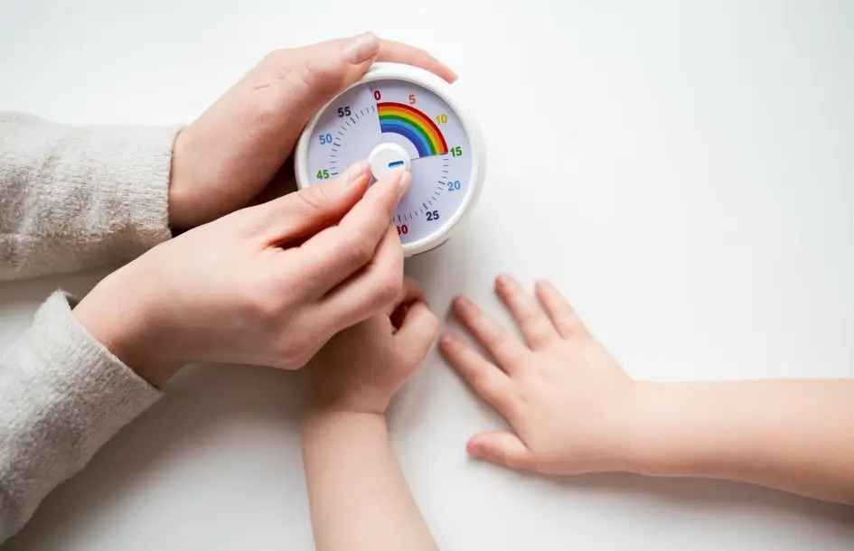 Transitioning between activities smoothly: Adult and child hands setting kids timer on white background.
