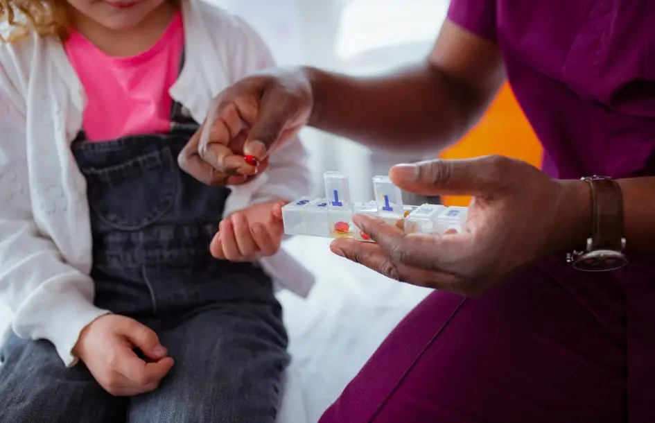 medication management in childcare. nurse or teacher giving child their daily medication