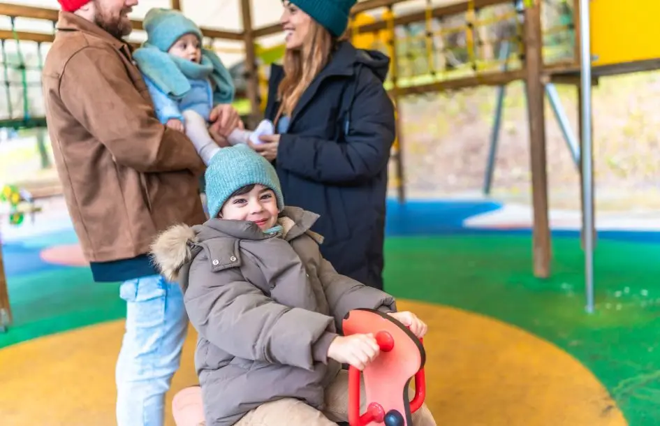 parents with their kids at playground rocking horsw for outdoor winter play