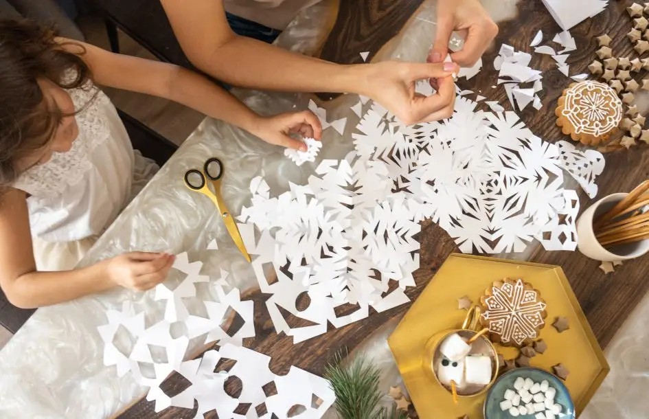 Mom and daughter cut snowflakes for winter crafts for kids