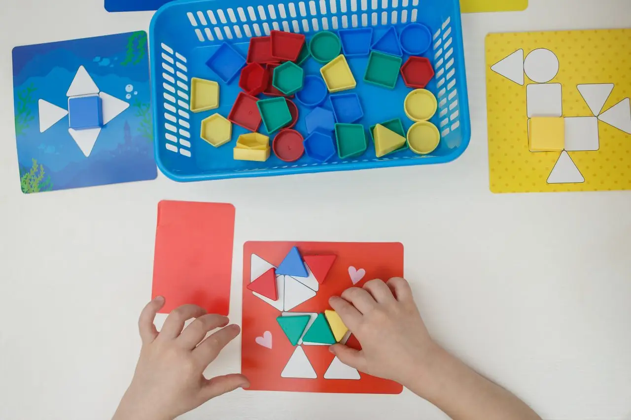 Toddlers playing multicolored educational games, mosaic and puzzles table. Building problem solving skills in preschoolers