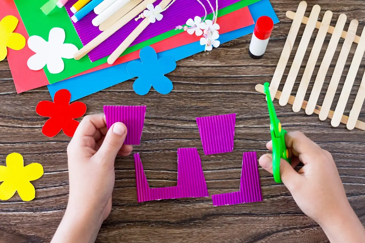 Child practice problem solving skills with open ended crafts. Childs hands cutting paper flowers