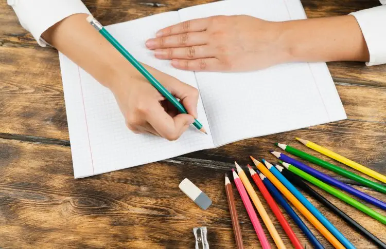 desk with notepad and colored pencils for creative writing activities for kids