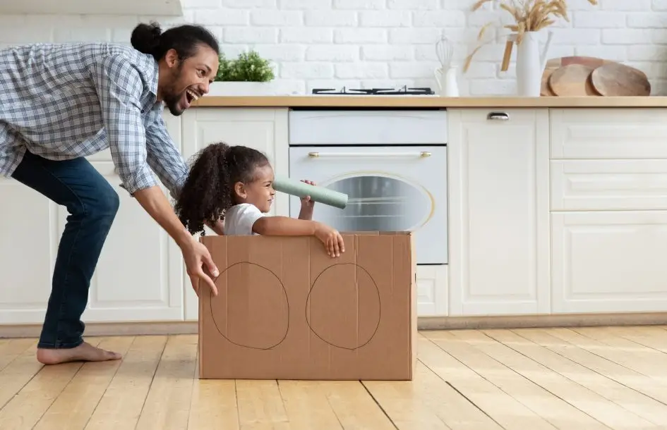 Imagination activities for kids: dad and daughter use cardboard box as a car and dad pushes it