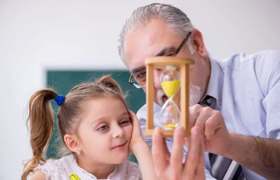 teacher and student look at hourglass timer, teaching preschoolers patience