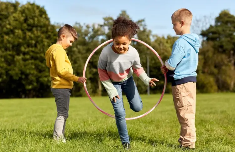 happy children playing game with hula hoop at park, movement boosting learning