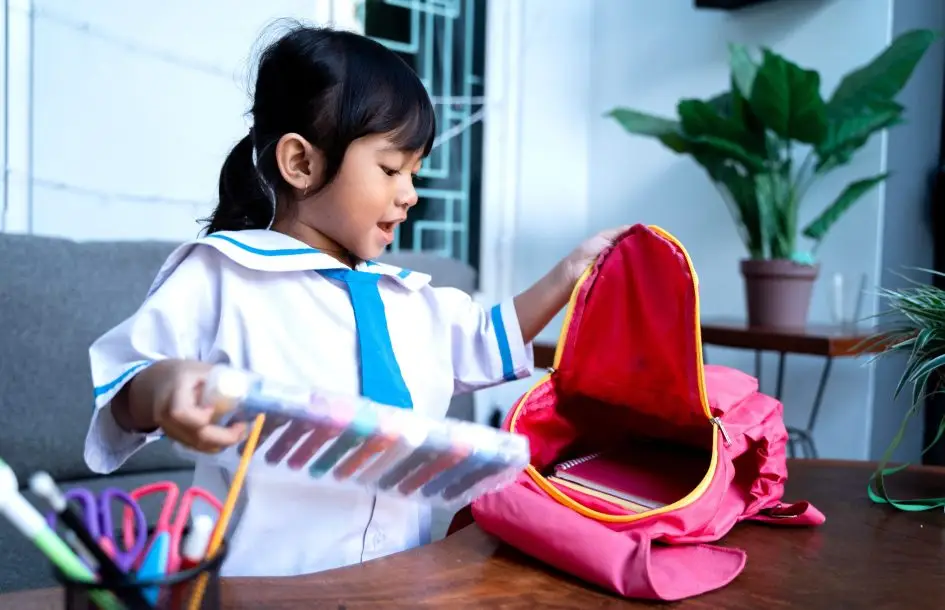 Building preschooler independent skills: independent young kindergarten student preparing her own stuff before going to school