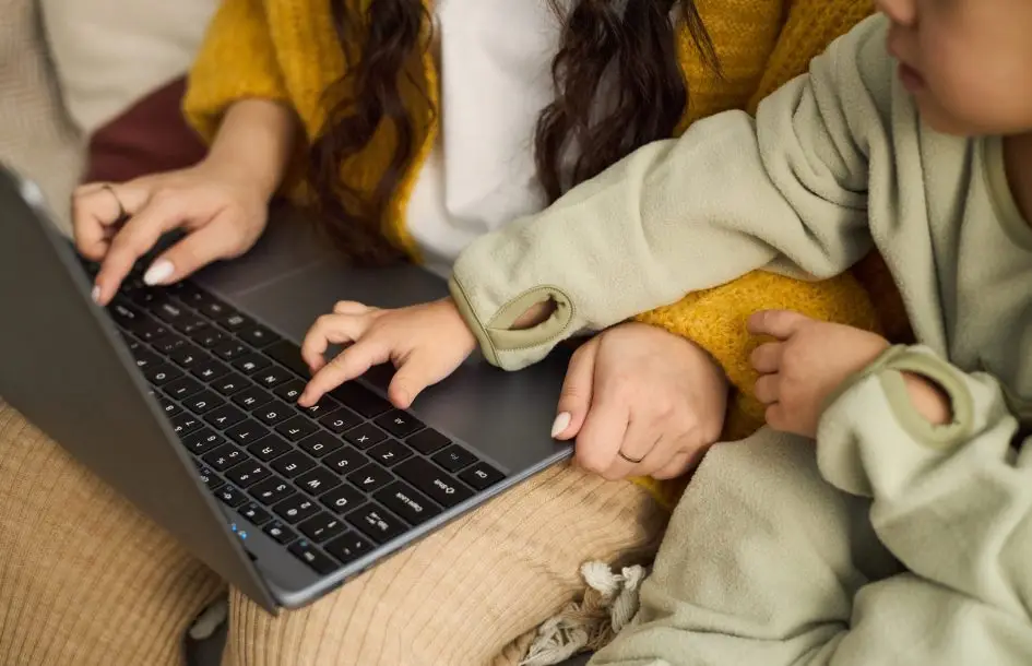 olney preschool enrollment process: child touching laptop keyboard while seated next to parent