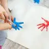 siblings children enjoy having fun together with mother painting brush and palm at home indoors . fourth of july crafts for kids