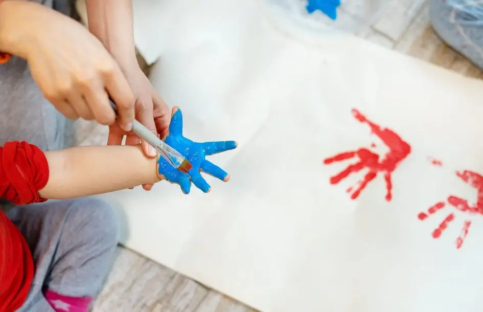 siblings children enjoy having fun together with mother painting brush and palm at home indoors . fourth of july crafts for kids
