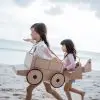 sibling and girl friend playing with cardboard airplane and car on the beach, summer stem activities of kids