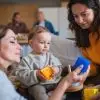 Happy multigeneration family playing with small baby indoors at home, visiting concept. Infant day care guide, day in the infant room