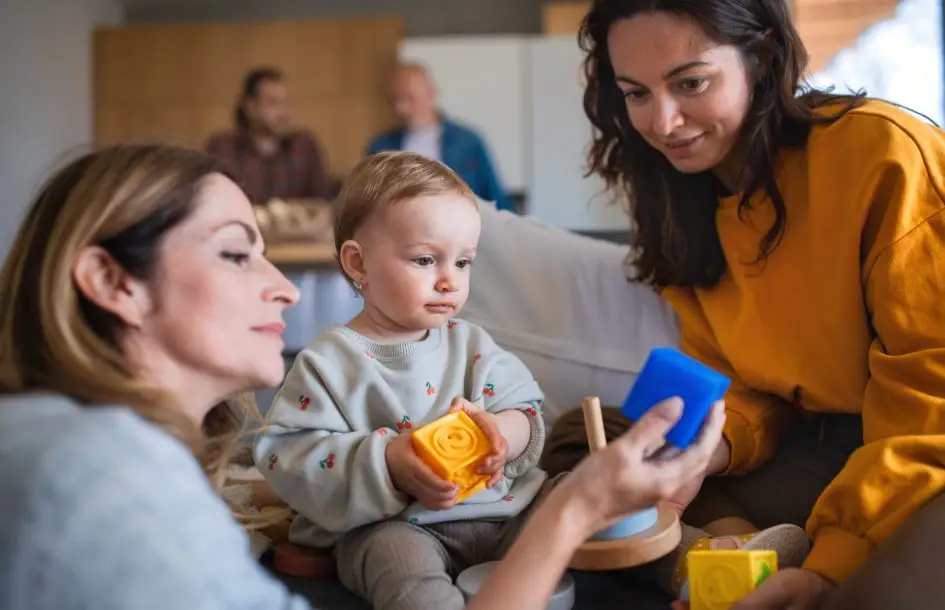 Happy multigeneration family playing with small baby indoors at home, visiting concept. Infant day care guide, day in the infant room