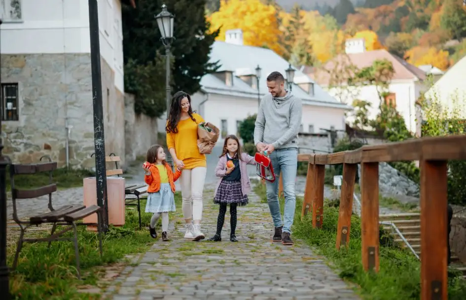 Family with two young daughters taking a nature walk in the park on the first day of fall