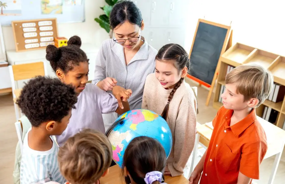 Diverse group of children exploring a globe with their teacher during International Day cultural activities
